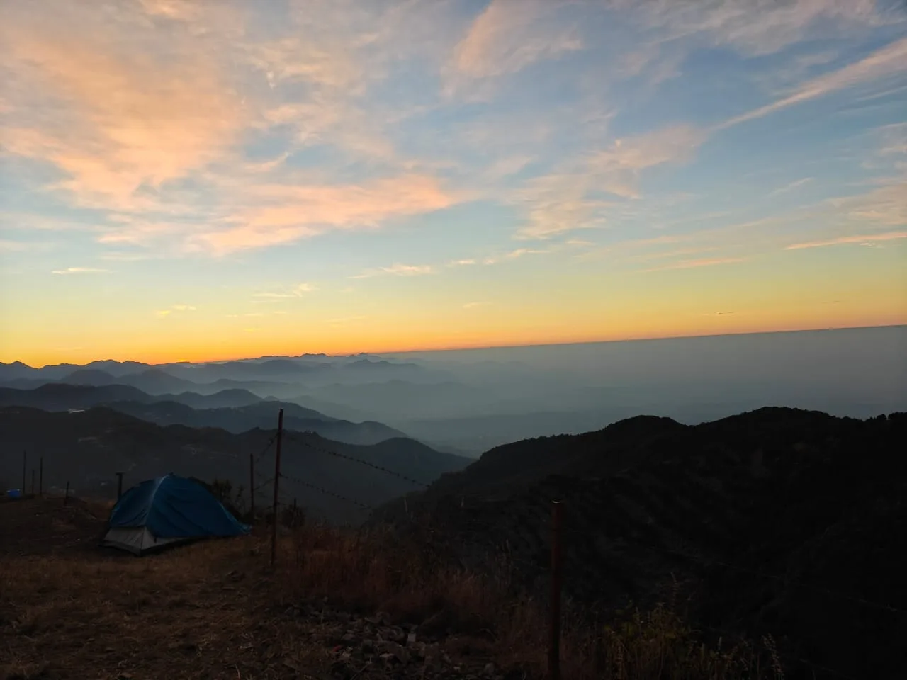 Tent at sunset with mountain layers