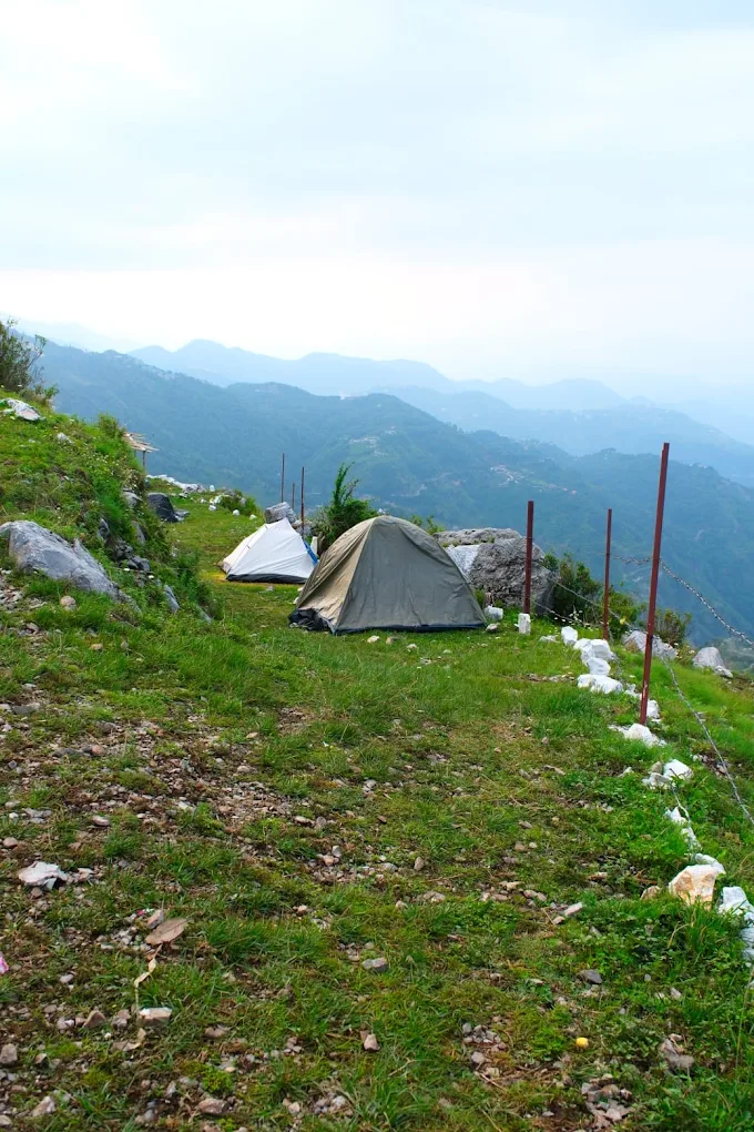 Tents on hillside with mountain panorama